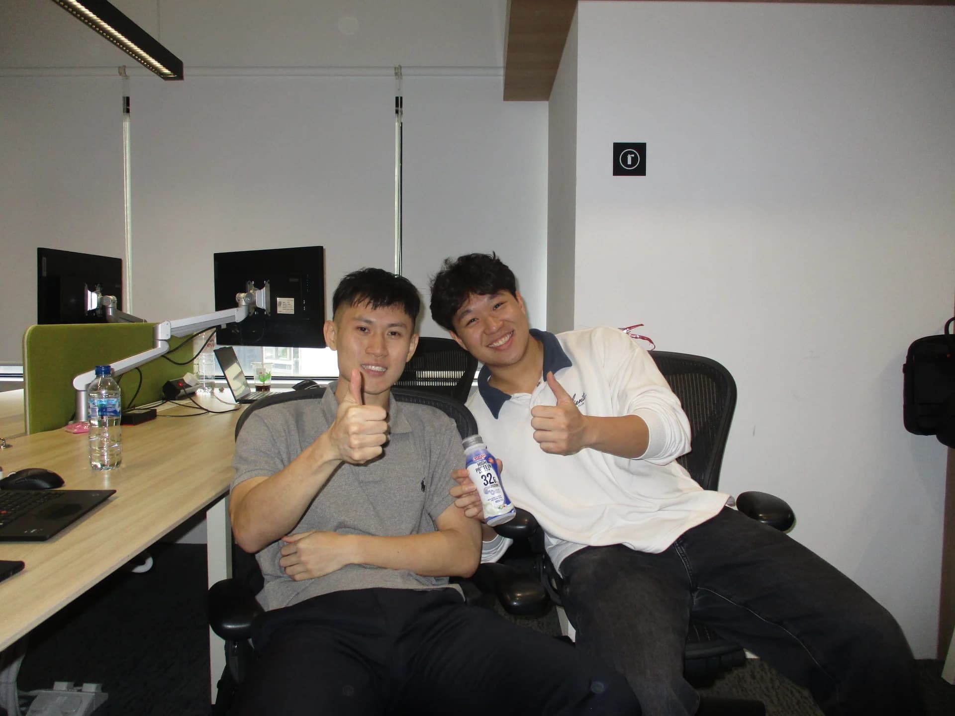 Matthias and Melville giving a thumbs-up at the EDBI office, with a bottle of Meiji protein milk