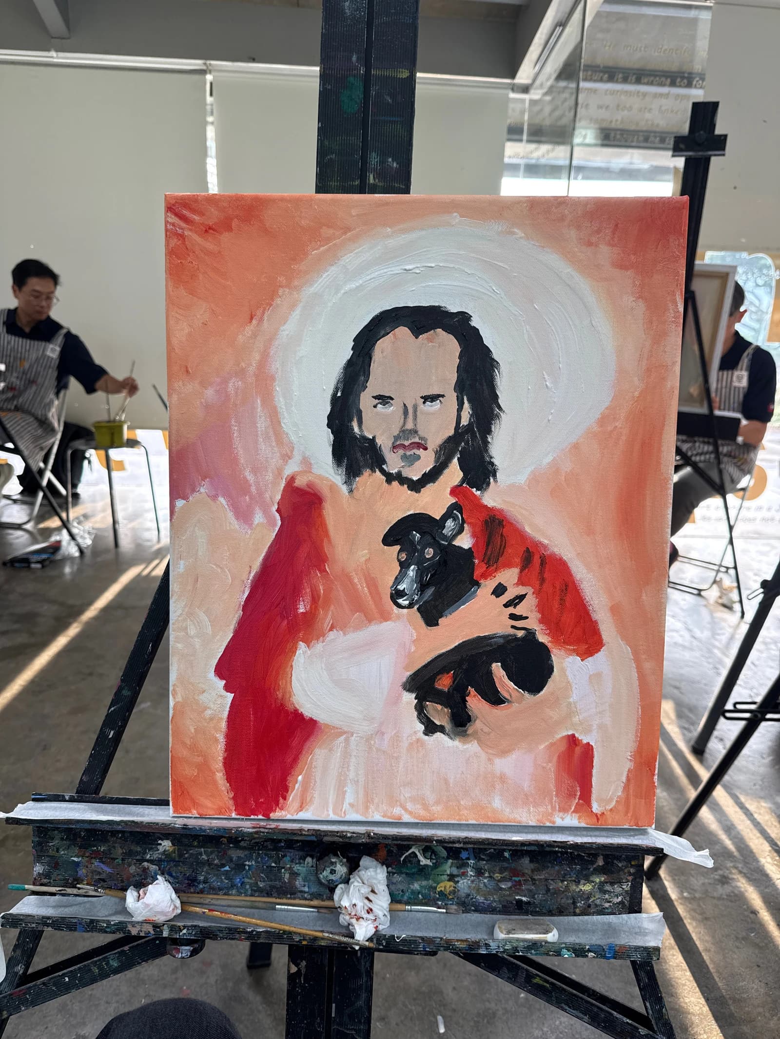 Matthias’s painting on an easel: a bearded figure in red holding a black dog